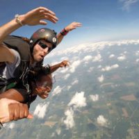 Tandem skydiving student and instructor with their arms in the air