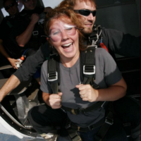 Happy tandem skydiving student about to jump from a plane