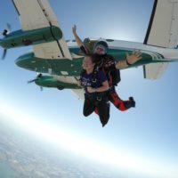 Tandem skydiving instructor spreading his arms as they jump from the plane