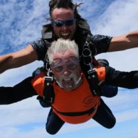 Older tandem skydiving student yelling for joy