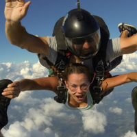 Tandem skydiving student holding onto her instructors feet