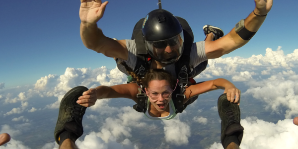 Tandem skydiving student holding onto her instructors feet
