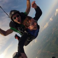 Tandem skydiving student hold onto instructors arm