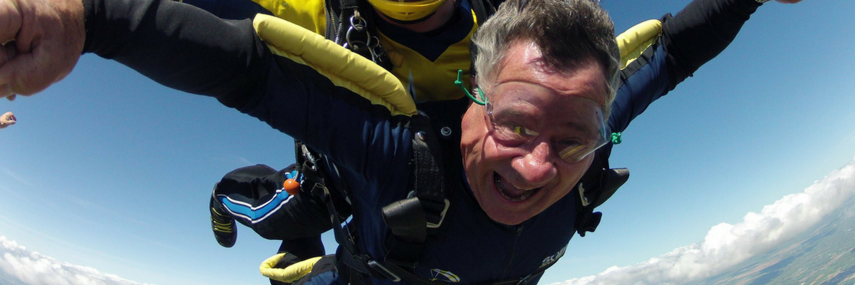 Tandem skydiving student smiles as he flies through the air with his instructor