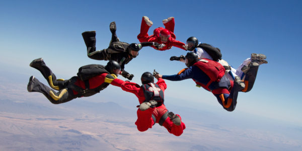 Skydivers holding hands in a circle while free falling