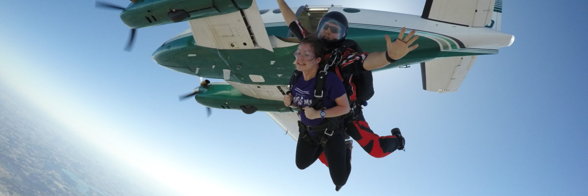 Tandem skydiving instructor spreading his arms as they jump from the airplane