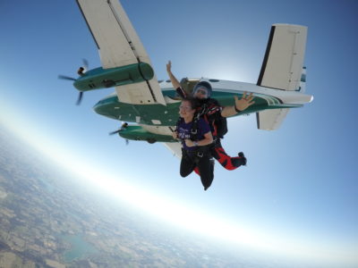 Tandem skydivers free falling with the plane in the background