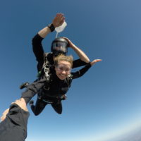 Tandem skydiver smiling at the camera while in free fall