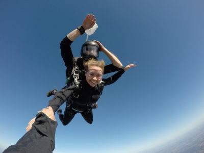 Excited skydiving student hold onto instructor