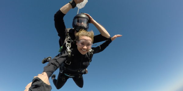 Tandem skydiver smiling at the camera while in free fall