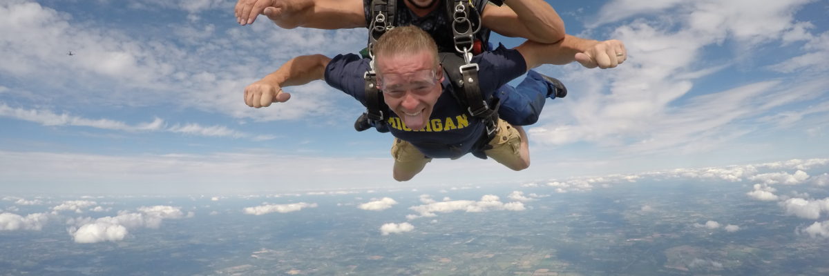 Tandem skydiving student sticks out his tongue during free fall