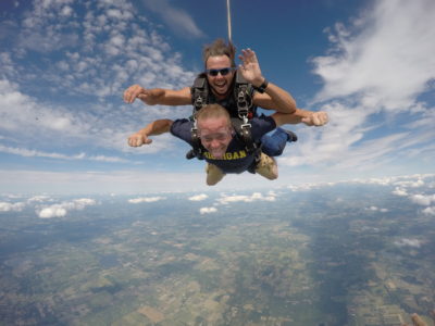 Tandem skydiving instructor waving at the camera during free fall