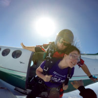 Tandem skydiving student hold on tight as the instructor jumps