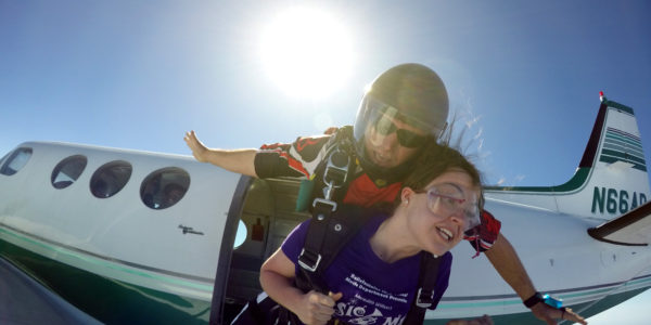 Tandem skydiving student hold on tight as the instructor jumps