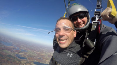 Happy looking tandem skydiving student during parachute ride