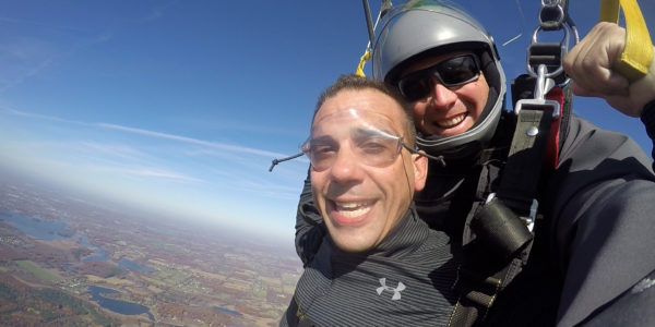 Tandem skydivers smiling at the camera during their parachute ride