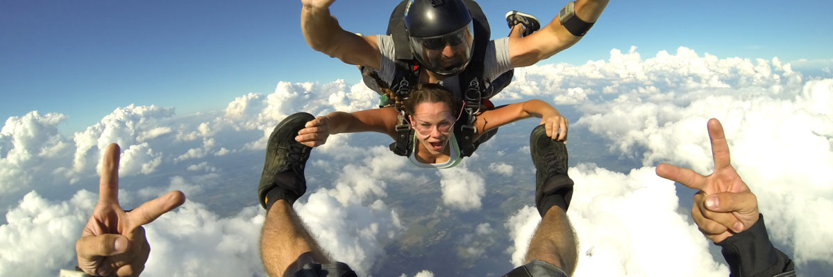 Tandem student holds onto skydiving instructors feet