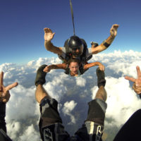 Tandem skydiving student holding onto instructors feet