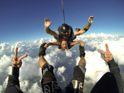 Tandem skydiving student grabs instructors feet during freefall