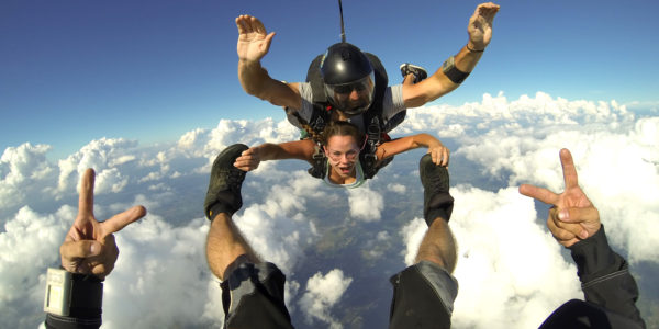 Tandem skydiving student holding onto instructors feet