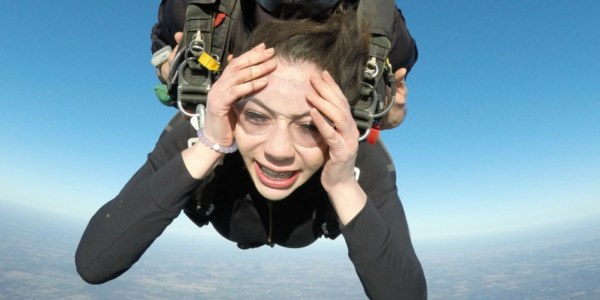 Tandem skydiving student holding her face