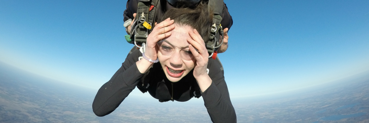 Tandem skydiving student holding her face