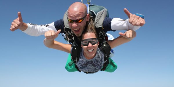 Tandem skydiving instructor and student giving their free fall two thumbs up