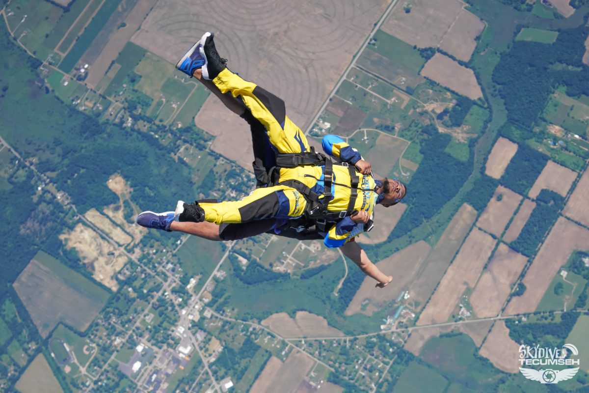 A tandem skydiving pair falling out of the aircraft into free fall