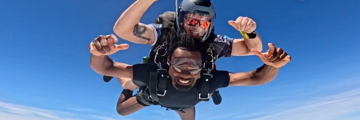 Tandem skydiving student smiles as he flies through the air with his instructor
